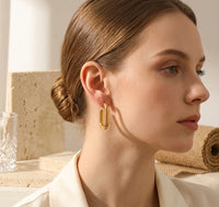 Close-up profile view of gold rectangle hoop earring worn on model's ear