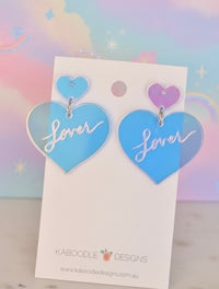 Pair of translucent blue acrylic heart drop earrings with 'Lover' script, on card backing