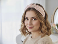 Woman wearing pastel pink striped knotted headband with wavy hair, front view