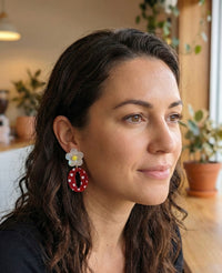 Close-up of daisy and red heart hoop earring worn on model's ear