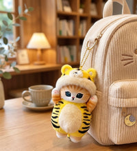 Mofusand cat plush keychain in yellow tiger costume clipped to a beige backpack