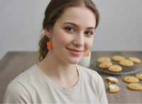 Model wearing orange biscuit dangle earrings, side profile view