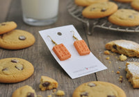 Close-up of biscuit earrings on card showing embossed dot detail and lettering