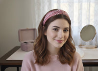 Woman wearing pink striped knot headband with hair down, front view