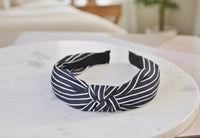 Black and white striped knotted headband on marble surface, side view