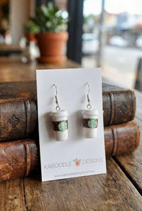 White resin coffee cup drop earrings with green logo detail, shown on Kaboodle Designs card