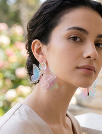 Iridescent butterfly earring worn on model's ear, close-up side view