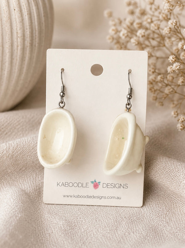 Pair of glossy white bathtub-shaped dangle earrings on a Kaboodle Designs card