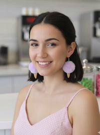 Woman wearing purple pom pom ice cream earrings styled with a pink polka dot top