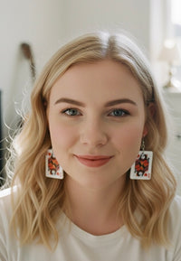 Close-up of woman wearing Joker and Queen playing card earrings