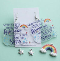 Pair of rainbow quote earrings displayed on card against mint green background
