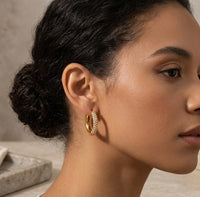 Close-up of gold pave hoop earring worn on model's ear, side profile