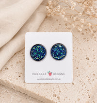 Midnight blue druzy-style stud earrings with green and silver flecks on a Kaboodle Designs card