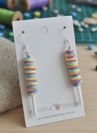 Rainbow twisty lollipop resin drop earrings on white card, front view