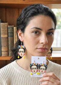 Woman wearing beaded portrait drop earrings with flower crown detail, close-up view
