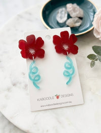 Red acrylic flower stud earrings with aqua curled tendril drops on card backing