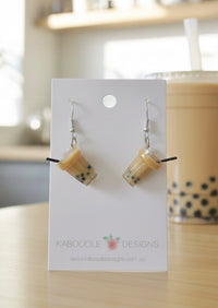 Pair of resin bubble tea cup earrings with tapioca pearls on a Kaboodle Designs card