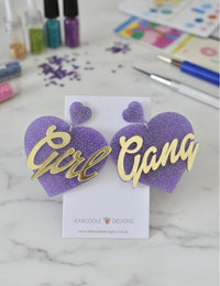 Purple glitter heart drop earrings with gold Girl Gang script on display card