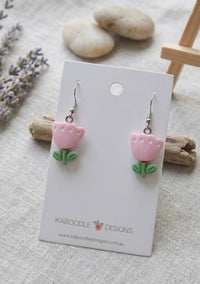 Pink resin tulip drop earrings with green stem on white display card