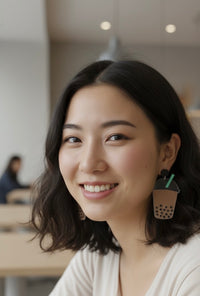 Close-up of boba earring worn on ear, showing glossy acrylic finish and straw detail