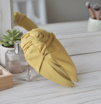 Mustard ruffled headband propped against a mirror on a dressing table