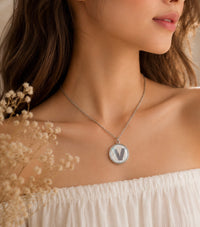 Close-up of letter V pendant necklace worn on model's neckline
