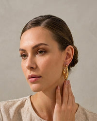 Model wearing textured gold hoop earring, side profile view