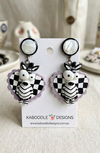 Acrylic zebra drop earrings with black and white checkerboard hearts on card backing