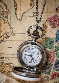 Open pocket watch necklace revealing white Quartz movement dial with black numerals on a map background