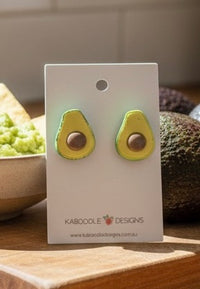 Pair of resin avocado stud earrings on a Kaboodle Designs card, showing pit detail