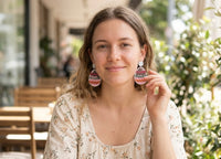 Woman wearing pink Easter egg glitter shaker drop earrings, close-up on model