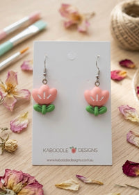 Pink resin tulip flower drop earrings with green leaves on Kaboodle Designs card