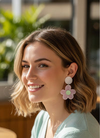 Pink daisy drop earring with white stud worn on model's ear, close-up side view