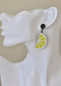 Close-up side view of a single lemon slice earring worn on an ear, showing yellow and white laser-cut detail
