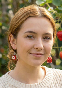 Close-up of jam toast and jam jar earrings worn on ear, front view