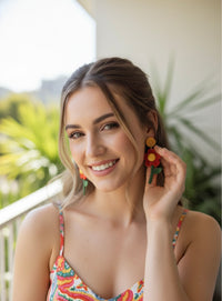Woman wearing red flower drop earring with mustard stud, close-up on model outdoors