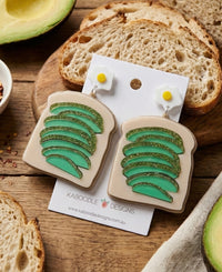 Perspex avocado toast drop earrings on card, with fried egg stud top and glittery green avocado slices on beige toast charm