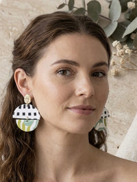 Model wearing geometric clay drop earrings featuring checkerboard and green marbled pattern, close-up on ear