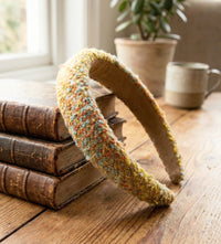 Boucle statement headband in yellow, coral and blue, propped against a stack of old books
