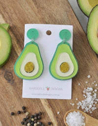 Green perspex avocado drop earrings with cream flesh and gold glitter stone, on card