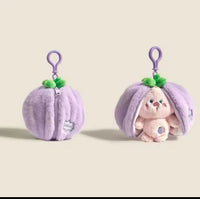 Purple fruit pouch keychain shown closed and unzipped to reveal pink plush creature inside