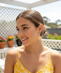 Close-up of model wearing a single cheese slice drop earring outdoors