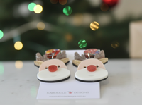 Front view of two reindeer earrings showing glossy red nose and gold glitter antlers