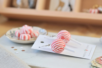 Pair of lollipop swirl earrings laid on a Kaboodle Designs card beside a dish of peppermints