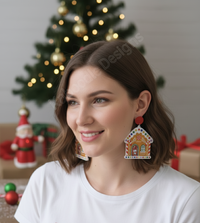 Woman wearing a gingerbread house drop earring with red circular stud, Christmas tree in background