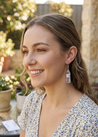 Close-up of Evian bottle earring worn on ear, showing blue cap and label detail