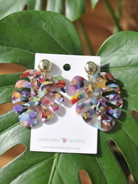 Multicolour acrylic monstera leaf earrings with gold stud tops on a Kaboodle Designs card