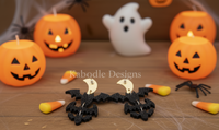 Close-up of acrylic bat and moon earrings showing glitter finish and tiered bat charms