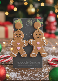 Resin gingerbread man drop earrings with white icing and pink heart detail on card
