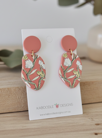 Coral acrylic statement earrings with white and gold botanical print on card backing